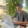 Mathieu Quentel, consultant SEO, travaillant sur son ordinateur portable dans un café lumineux entouré de verdure